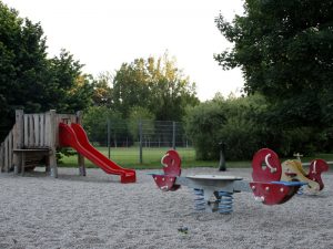 Rutsche udn Wippe mit Sand am Kleinkinderspielplatz im Auer Welsbach Park